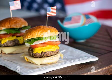 American beef burger and Cookies with American flag icing for independence day and an American flag for background Stock Photo