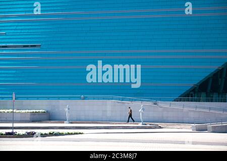 Man figure walking in front of blue color modern architecture facade of Kazakhstan Central Concert Hall, urban life in Astana - capital of Kazakhstan Stock Photo