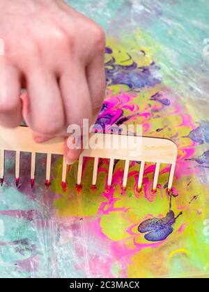 workshop of Ebru paper marbling - mixing of dyes with wooden comb on surface of liquid in plastic basin for printmaking Stock Photo
