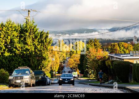 VANCOUVER, CANADA - Oct 22, 2019: A steep street slopes down towards the waterfront of Kitsilano in Vancouver, with the north shore mountains beyond. Stock Photo