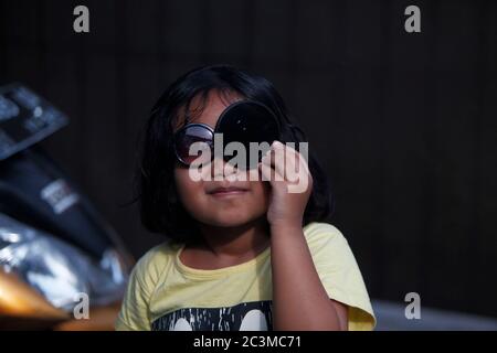 Bogor, Indonesia. 21st June, 2020. A girl watches the partial solar eclipse using a lens filter in Bogor, West Java, Indonesia, on June 21, 2020. (Photo by Adriana Adinandra/INA Photo Agency/Sipa USA) Credit: Sipa USA/Ģ����ý Live News Stock Photo