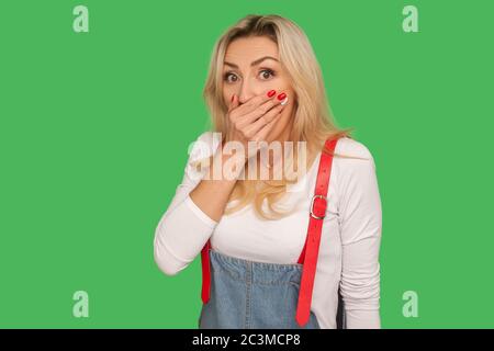 I won't speak! Portrait of frightened intimidated adult woman covering mouth with hand and looking scared, afraid to tell truth, keeping terrifying se Stock Photo