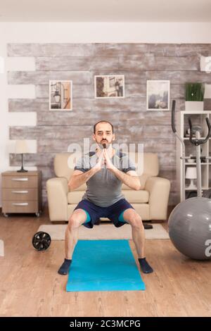 Fit man training his legs on yoga mat during global pandemic. Stock Photo