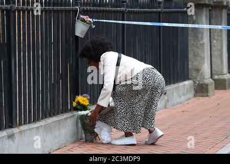 A woman places some flowers at the Abbey gateway of Forbury Gardens in Reading town centre following a multiple stabbing attack in the gardens which took place at around 7pm on Saturday leaving three people dead and another three seriously injured. Stock Photo