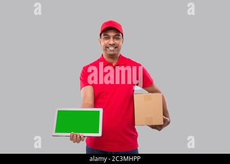 Indian Delivery Man Holding Tablet and Carpet Box. Delivery Boy Smilling Isolated Stock Photo
