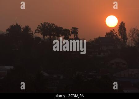 Beautiful Sunrise Behind a Temple and Palms at Laos, seen from Chiang Khong, Thailand, Asia Stock Photo