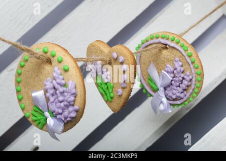 Gingerbread cookies decorated with glaze. On some ribbons tied to a bow. Gingerbread cookies are round and in the shape of a heart. Hanging on a rope. Stock Photo