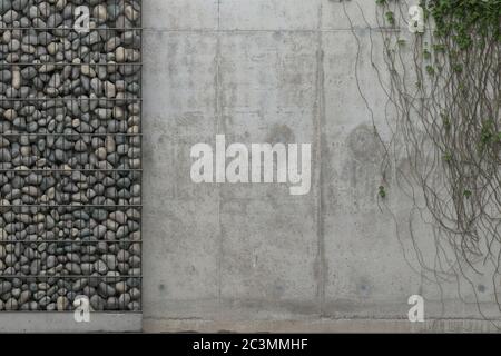 Background with gray concrete wall and gabion wall with stones in a metal grid frame. Front view with copy space. 3D rendering. Stock Photo