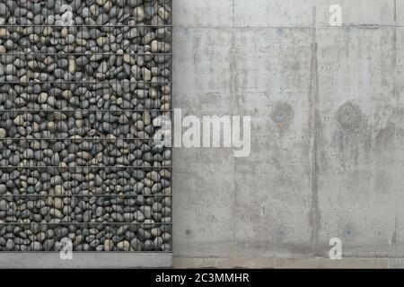 Background with gray concrete wall and gabion wall with stones in a metal grid frame. Front view with copy space. 3D rendering. Stock Photo