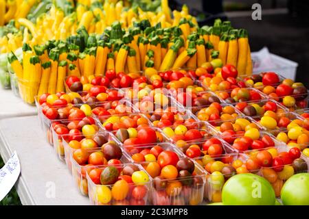 Display of multi-colored cherry tomatoes and fresh cut baby squash at an outdoor farmer's market Stock Photo