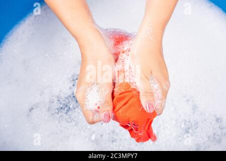 Closeup young Asian woman use hands washing color clothes in basin with detergent have soapy bubble water, studio shot background, laundry concept Stock Photo