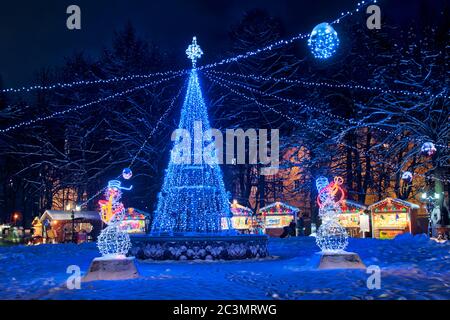 = Christmas Tree and Snowmen at Park Lipki (Vladimir) =  Illuminated with LED lights Christmas tree with garlands and snowmen playing saxophone on the Stock Photo