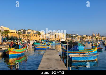 Marsaxlokk fishing village port in Malta, Traditional Maltese Luzzu boats and the skyline. Stock Photo