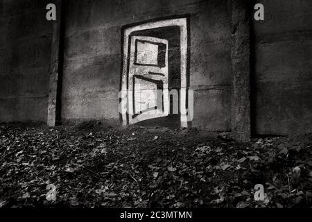 Old concrete wall in the woods with simple mural of door, portal to the other side in black and white, minimalistic graffiti Stock Photo