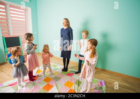 Chilren with teacher standing in circle and clapping hands. Greetings song. Stock Photo