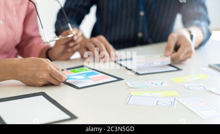 Graphic designers team work together with UX UI designer planning application template layout mobile phone prototype, User experience concept. Stock Photo
