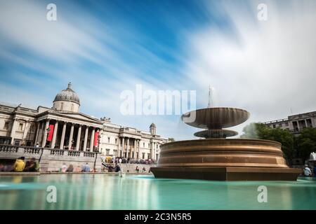 Groups of tourists and locals enjoy the sunshine at the main entrance to the National Gallery in Trafalgar Square. The gallery houses the national col Stock Photo