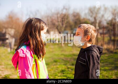 Brother and sister in protective masks outdoors Stock Photo