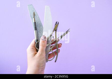 Hand holding Manicure and pedicure tools on pink background. Nail salon banner design template. Beauty treatment concept Stock Photo