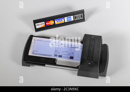 Manual credit card machine - old technology - a manually operated credit card imprinter with credit card logos - personal check sign Stock Photo