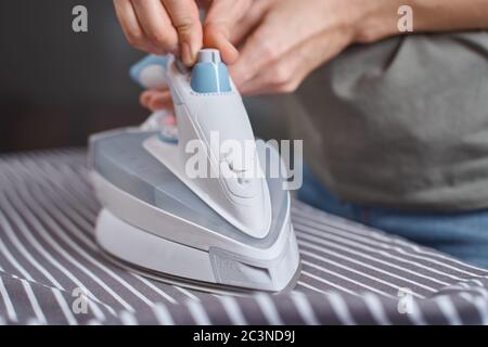Woman ironing clothes on ironing board with modern iron Stock Photo