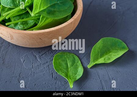 Fresh spinach leaves in wooden bowl on a dark background. Organic food Stock Photo