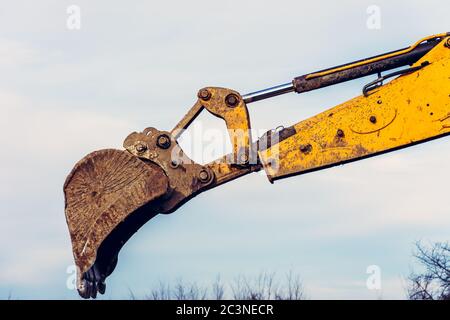 A close-up excavator loads soil into the bucket for further road installation. Stock Photo