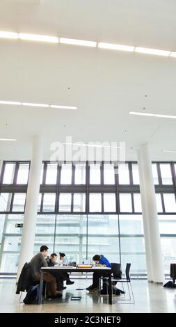 PAMPLONA, SPAIN - Dec 27, 2014: Nice photo in high key of some young people studying in a very bright and modern library. Stock Photo