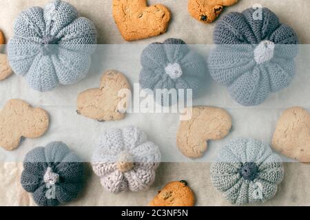 Autumn still life from handcrafted knitted pumpkin, cookies in heart shape on baking paper. Concept warm cozy home fall season comfort. Mock up Stock Photo