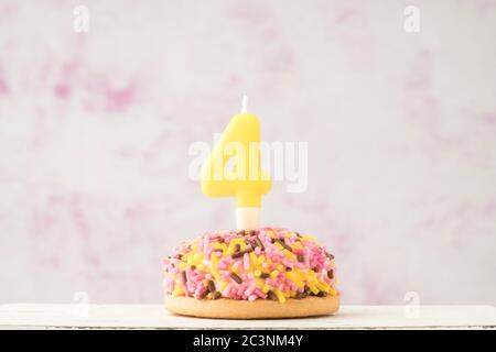 a small coloruful cupcake with number four shaped candle for birthday celebration Stock Photo