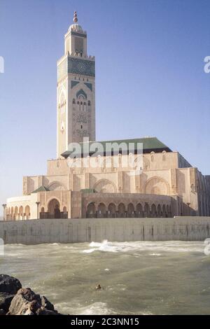 A man swimming in the ocean in front of the mosque Hassan II in Casablanca, Morocco, during an afternoon in Autumn Stock Photo