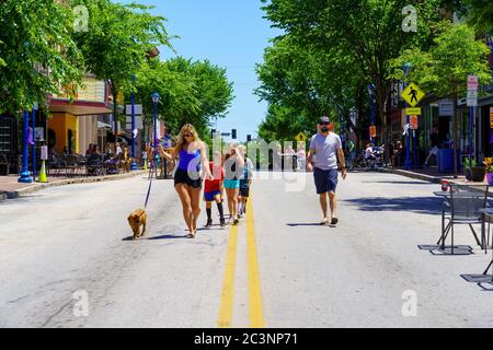 Phoenixville, PA, USA - June 14, 2020: Socially distanced, pedestrians walk in the middle of a closed street in the town. Stock Photo