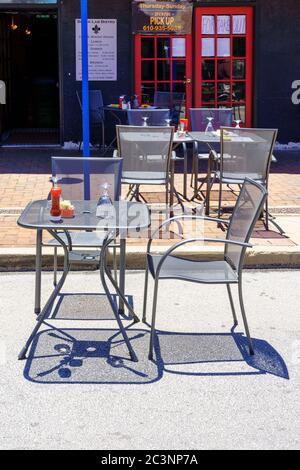 Phoenixville, PA, USA - June 14, 2020: Socially distanced tables are appropriately positioned along the main street in the town. Stock Photo