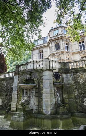 Le Port-Marly, France - June 24, 2018: Old stone fountain with sculptures (dragon pool) near The Chateau de Monte-Cristo is a house museum of the writ Stock Photo