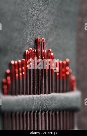 Sewing needles of different sizes in a set of red on a black background. Stock Photo