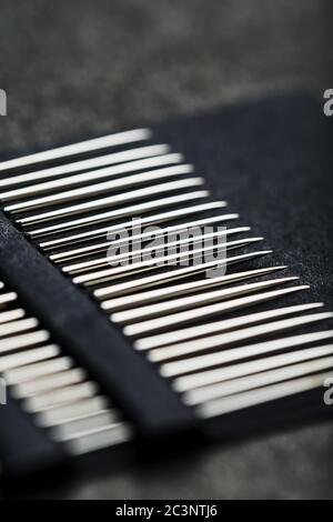 Gold sewing needles on a black background in a row. Stock Photo