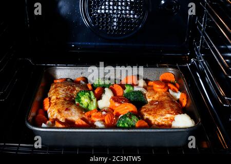 Roasted chicken with vegetables in the oven. Cooking time Stock Photo