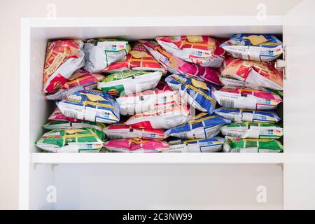 London, England / UK - June 2nd 2020: Crisp packets stacked in kitchen cupboard as unhealthy eating habits increase Stock Photo