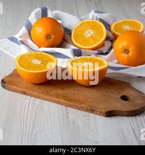 Halved and whole oranges on a white wooden background, side view. Stock Photo