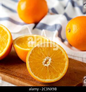 Halved and whole oranges on a rustic board, side view. Close-up. Stock Photo