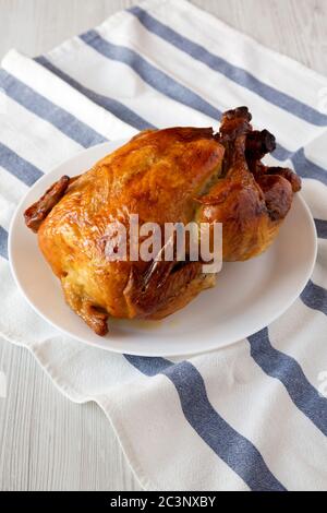 Homemade traditional rotisserie chicken on a white plate, side view. Stock Photo