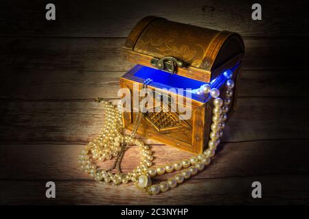 Vintage wooden box, full with jewellery, blue light inside Stock Photo