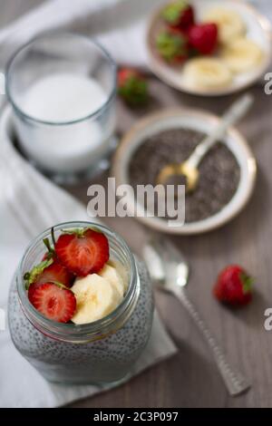 Healthy vegan chia seed pudding in a mason jar topped with strawberry and banana. Rustic and dark concept Stock Photo