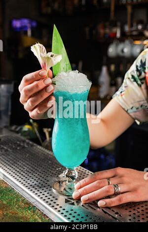 Lady bartenger garnishing blue hawaii cocktail with a flower Stock Photo