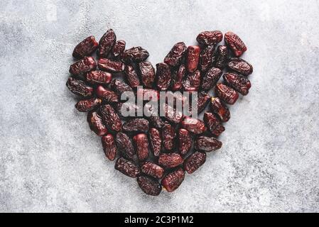 Dried date fruits on concrete background in shape of heart. Healthy arabic vegetarian food Stock Photo