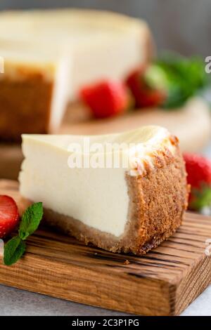 Slice of plain classical cheesecake on wooden board closeup view, copy space Stock Photo