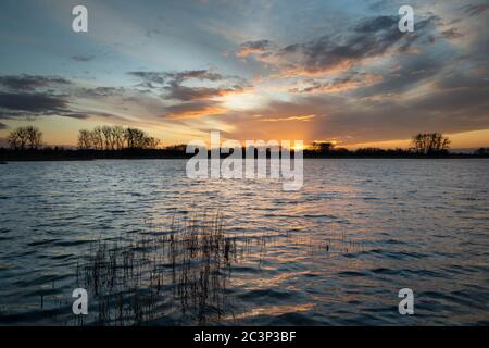 Beautiful clouds and sunset on a quiet lake with reeds, evening spring view Stock Photo