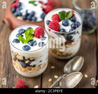 White yogurt in two bowls with blueberries, raspberries on natural wooden desk. Stock Photo