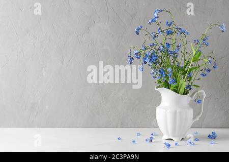 Spring or summer blue flowers forget me not in vase on concrete background. Still life. Holiday or wedding background Stock Photo