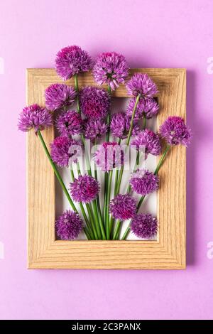 Creative layout made with purple flowers in picture frame on purple background. Flat lay. Flower composition. vertical orientation Stock Photo